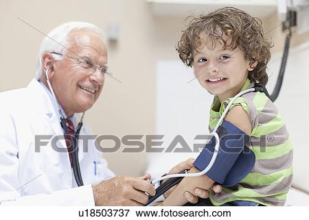 Stock Photo - Doctor examining boy in office. Fotosearch
