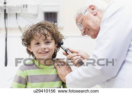 Stock Photograph - Doctor examining boy in office. Fotosearch