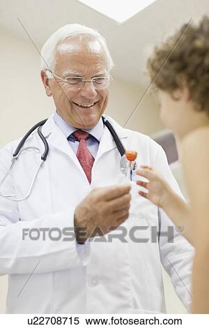 Doctor giving boy lollipop in office View Large Photo Image Stock Photography - Doctor giving boy lollipop in office. Fotosearch