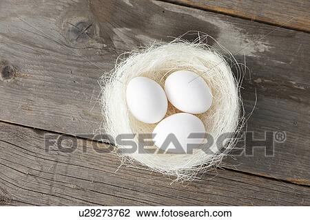 Stock Image - Eggs in nest on wooden counter. Fotosearch