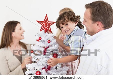 Stock Image - Family decorating Christmas tree. Fotosearch