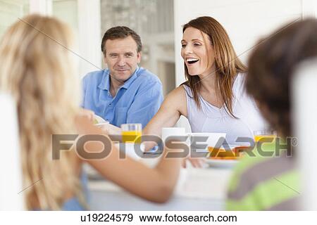 Stock Photo - Family eating together at table. Fotosearch