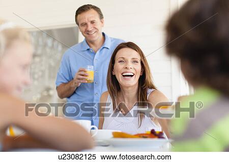 Stock Photography - Family eating together at table. Fotosearch