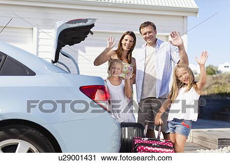 Stock Image - Family loading up car trunk for vacation. Fotosearch