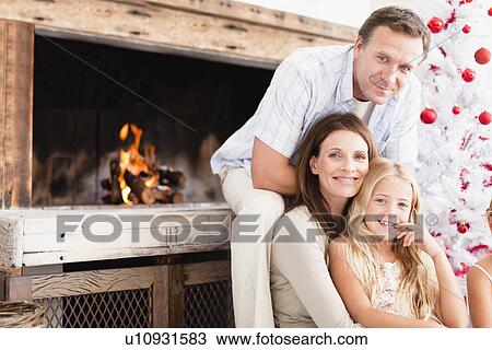 Family relaxing by Christmas tree View Large Photo Image Stock Image - Family relaxing by Christmas tree. Fotosearch