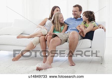 Stock Image - Family relaxing together on sofa. Fotosearch