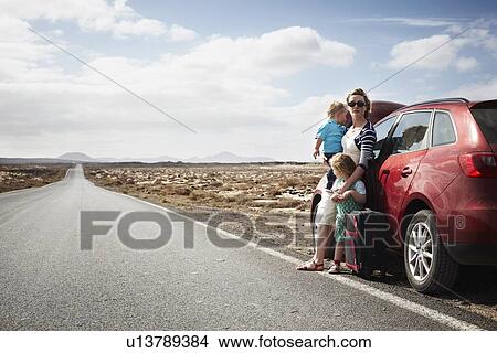 Picture - Family standing by broken down car. Fotosearch
