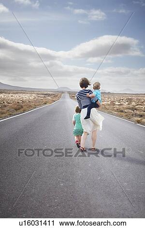 Stock Image - Family walking on paved rural road. Fotosearch