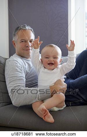 Stock Image - Father and baby relaxing on sofa. Fotosearch