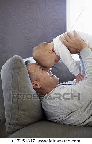 Father and baby relaxing on sofa View Large Photo Image Stock Photo - Father and baby relaxing on sofa. Fotosearch