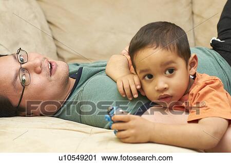 Father and son relaxing on sofa View Large Photo Image Stock Image - Father and son relaxing on sofa. Fotosearch