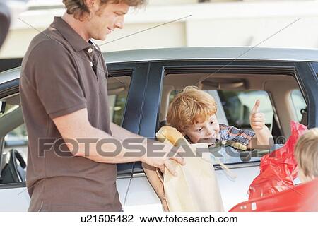 Stock Image - Father and sons loading groceries in car. Fotosearch