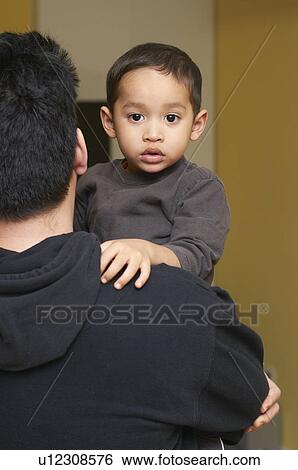 Stock Photograph - Father carrying son indoors. Fotosearch