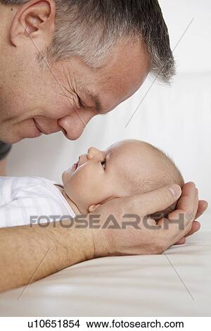 Father cradling baby on bed View Large Photo Image Picture - Father cradling baby on bed. Fotosearch