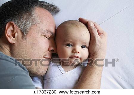 Father cradling infant in bed View Large Photo Image Stock Image - Father cradling infant in bed. Fotosearch