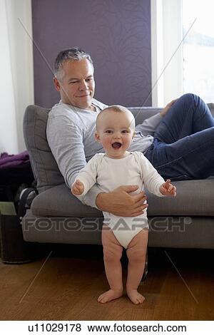 Stock Photo - Father helping toddler stand up. Fotosearch