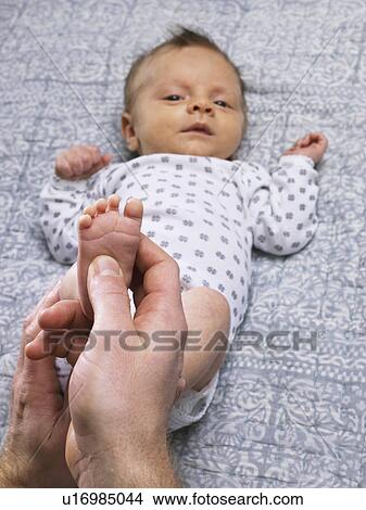 Picture - Father tickling infants feet on table. Fotosearch