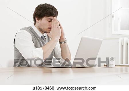 Stock Photo - Frustrated businessman thinking at desk. Fotosearch