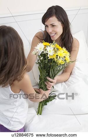 Stock Photography - Girl bringing mother bouquet of flowers. Fotosearch