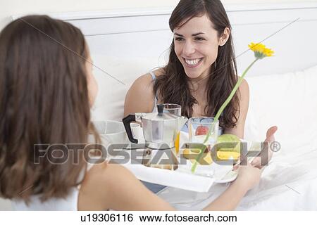 Stock Photograph - Girl bringing mother breakfast in bed. Fotosearch