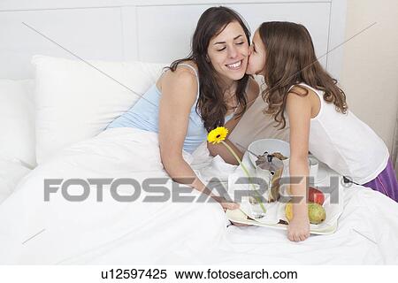 Stock Photography - Girl bringing mother breakfast in bed. Fotosearch