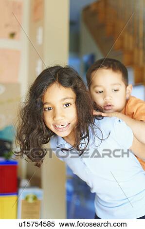 Stock Photography - Girl carrying brother piggyback. Fotosearch