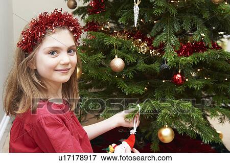 Girl decorating Christmas tree View Large Photo Image Stock Photo - Girl decorating Christmas tree. Fotosearch