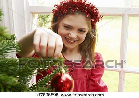 Girl decorating Christmas tree View Large Photo Image Stock Photo - Girl decorating Christmas tree. Fotosearch