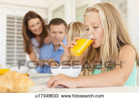 Stock Image - Girl drinking orange juice at breakfast. Fotosearch