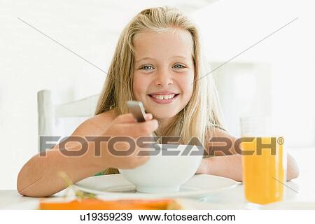 Stock Photo - Girl eating cereal at breakfast table. Fotosearch