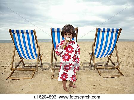 Stock Image - Girl eating ice cream on beach. Fotosearch