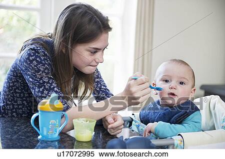 Girl feeding baby brother at table View Large Photo Image Stock Photography - Girl feeding baby brother at table. Fotosearch