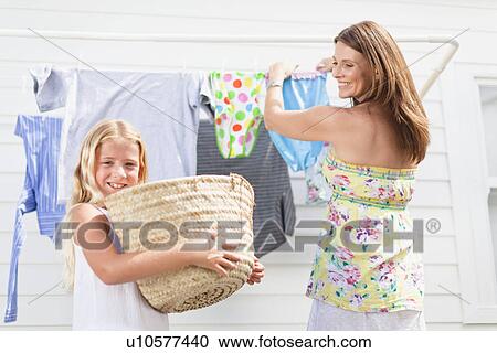 Girl helping mother hang laundry View Large Photo Image Stock Image - Girl helping mother hang laundry. Fotosearch