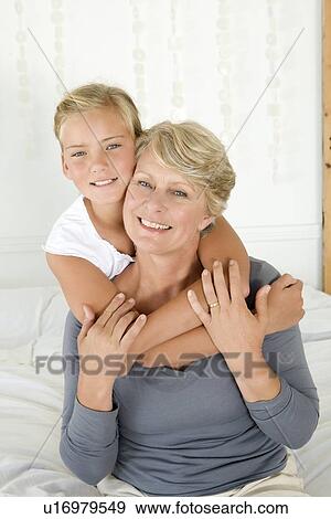 Girl hugging grandmother on bed View Large Photo Image Stock Photo - Girl hugging grandmother on bed. Fotosearch