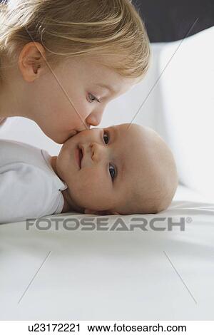 Girl kissing baby sibling on bed View Large Photo Image Stock Image - Girl kissing baby sibling on bed. Fotosearch