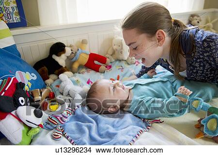 Girl playing with baby brother on bed View Large Photo Image Picture - Girl playing with baby brother on bed. Fotosearch
