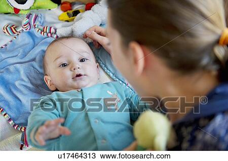 Stock Image - Girl playing with baby brother on bed. Fotosearch