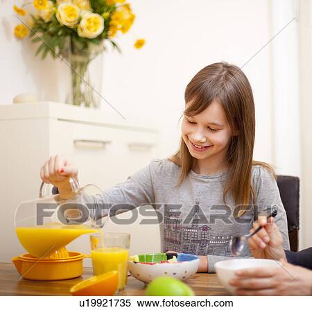 Girl pouring orange juice at table View Large Photo Image Stock Photography - Girl pouring orange juice at table. Fotosearch