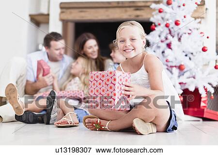 Girl sitting with wrapped Christmas gift View Large Photo Image Stock Photo - Girl sitting with wrapped Christmas gift. Fotosearch