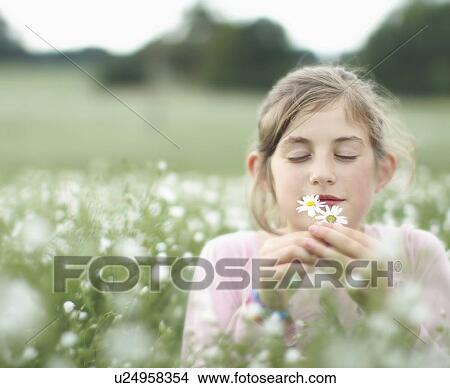 Girl smelling flowers in meadow View Large Photo Image Picture - Girl smelling flowers in meadow. Fotosearch