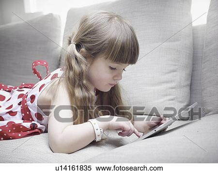 Girl using tablet computer on sofa View Large Photo Image Stock Photography - Girl using tablet computer on sofa. Fotosearch