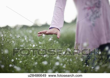 Stock Photo - Girl walking in field of flowers. Fotosearch