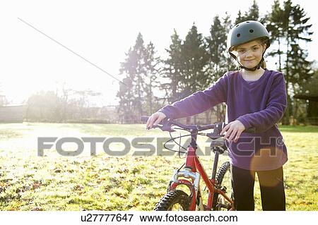 Stock Photo - Girl walking with bicycle in meadow. Fotosearch