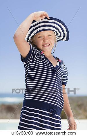Stock Image - Girl wearing sunhat outdoors. Fotosearch