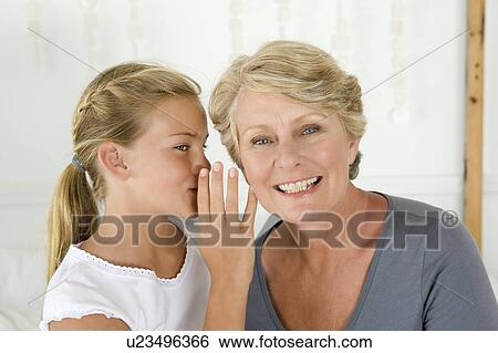 Stock Photograph - Girl whispering to grandmother. Fotosearch