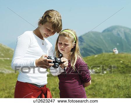 Stock Photo - Girls examining camera outdoors. Fotosearch