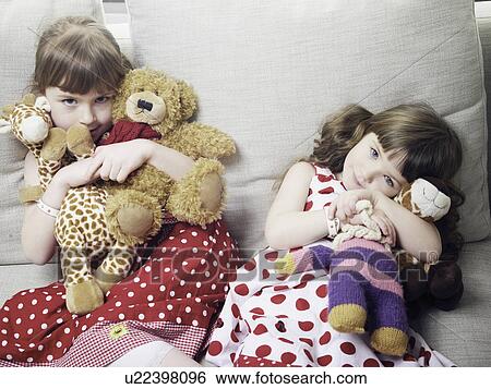 Stock Photograph - Girls holding stuffed animals on sofa. Fotosearch
