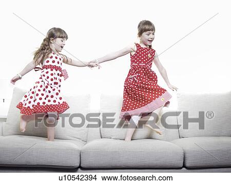 Picture - Girls playing together on sofa. Fotosearch