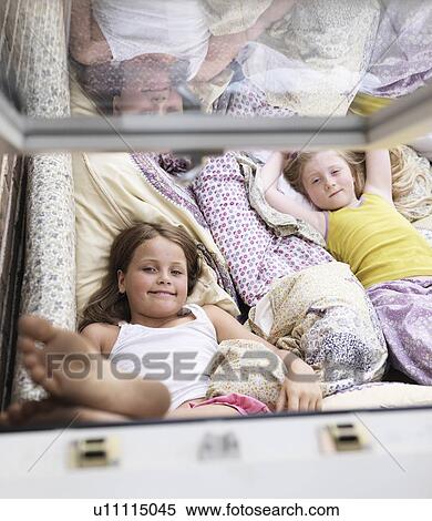 Stock Photography - Girls relaxing on sofa indoors. Fotosearch