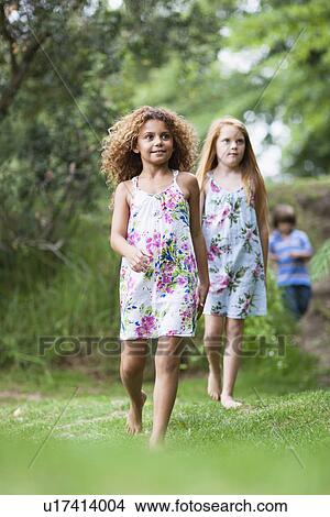 Girls walking in grass together View Large Photo Image Picture - Girls walking in grass together. Fotosearch